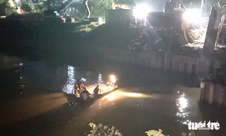Lực lượng cứu hộ cứu nạn chong đèn, dùng thuyền tìm kiếm nạn nhân mất tích trong vụ ô tô tông hai xe máy rồi rơi xuống sông ở Nghệ An trong đêm 13-7 - Ảnh: DOÃN HÒA