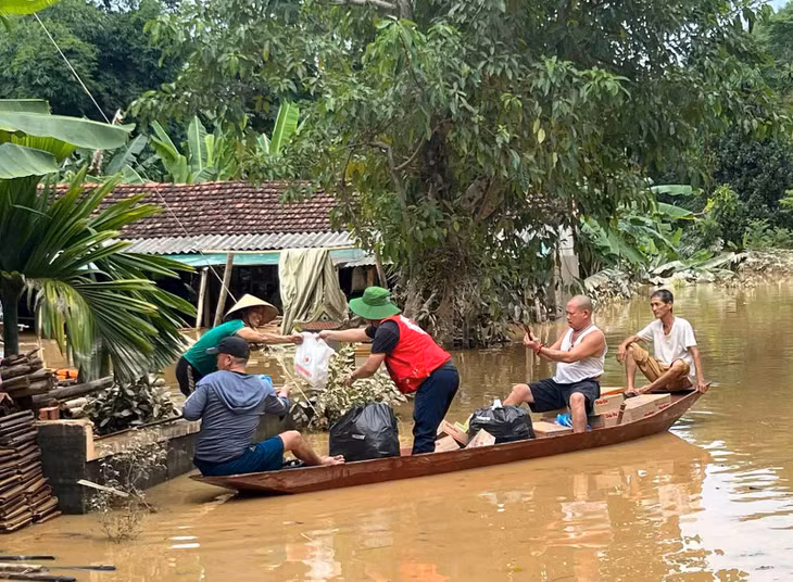 Cán bộ Hội Chữ thập đỏ dùng thuyền để chuyển hàng cứu trợ đến từng hộ gia đình. Ảnh: Hải Dương