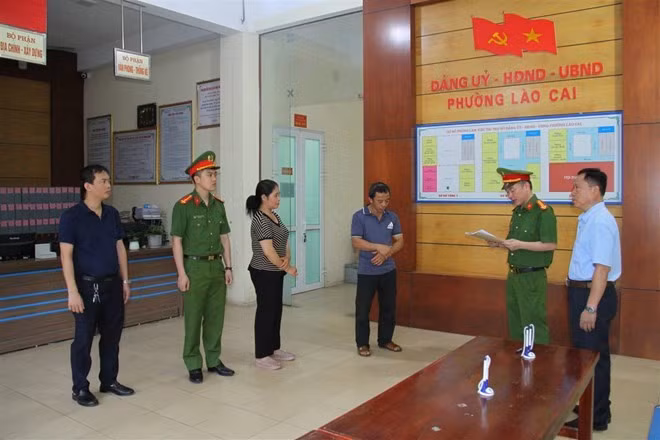 Công an đọc quyết định khởi tố vợ chồng Tạ Văn Hải và Lê Thị Thắm (chắp tay phía trước). Ảnh: Công an cung cấp