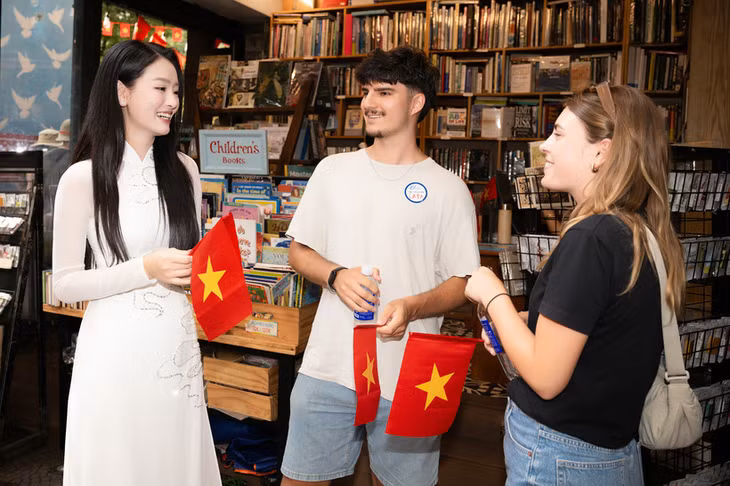 Du khách quốc tế hào hứng vì được tặng lá cờ đỏ sao vàng khi trải nghiệm điểm đến Thành phố Hồ Chí Minh. (Ảnh: CTV/Vietnam+)