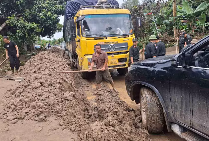 Thông tuyến tạm nhưng bùn đất hai bên Quốc lộ 7 vẫn còn rất nhiều, công việc dọn sạch hết cũng còn rất gian nan. Ảnh: Trần Tuấn.