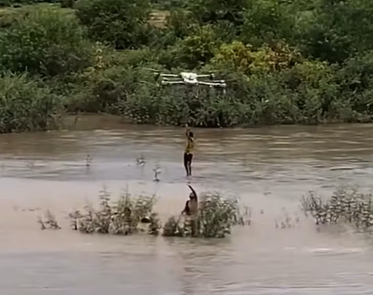 Khoảnh khắc kịch tính khi máy bay không người lái "cẩu" 1 trong 2 em nhỏ bị mắc kẹt giữa dòng nước xiết vào bờ - Ảnh cắt từ video