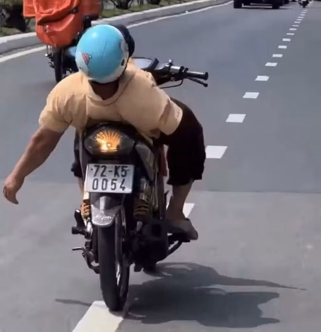 Hình ảnh người đàn ông cụt tay phải vẫn lái xe máy, buông luôn tay còn lại ngả người ra sau như diễn xiếc. Ảnh cắt từ clip