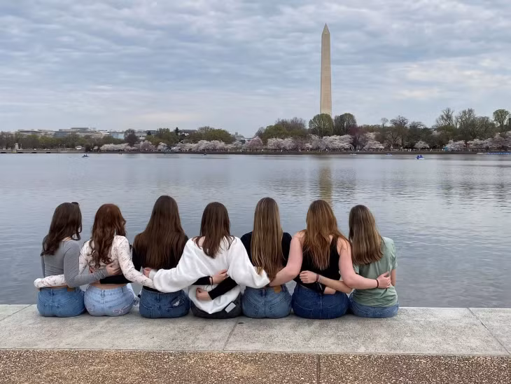 Nhóm bạn ngồi trên bờ Tidal Basin gần Đài tưởng niệm Jefferson vừa ngắm cảnh hoa đào nở vừa chụp ảnh kỷ niệm. Ảnh: Will Dunham/Reuters.