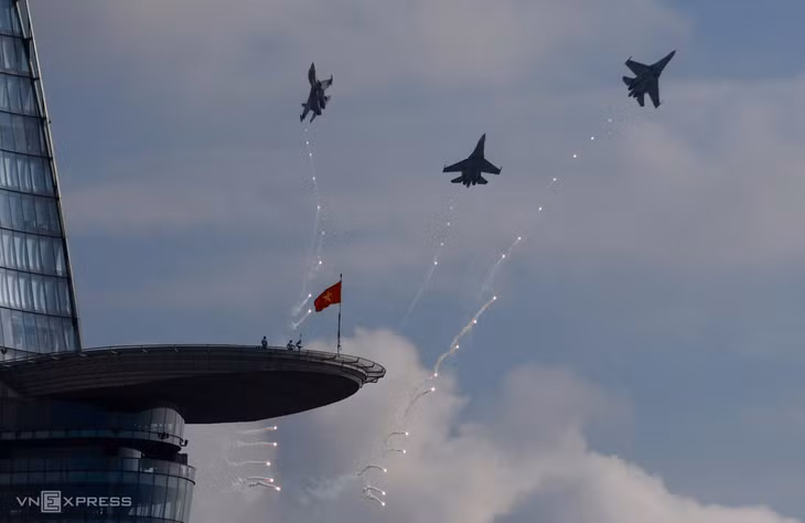 Lúc 8h10 ngày 27/4, hàng chục tiêm kích, trực thăng từ sân bay Biên Hòa tiến về TP HCM tham gia lễ tổng duyệt diễu binh 50 năm thống nhất đất nước. Khi tới trung tâm thành phố, biên đội tiêm kích Su-30MK2 nhào lộn nhiều vòng, sau đó thả bẫy nhiệt trên bầu trời. Trong ảnh là ba tiêm kích bay qua tòa Bitexco 68 tầng, cao gần 270 m, xếp thứ hai tại TP HCM. Công trình hướng ra sông Sài Gòn, cách Dinh Độc Lập chừng một km.