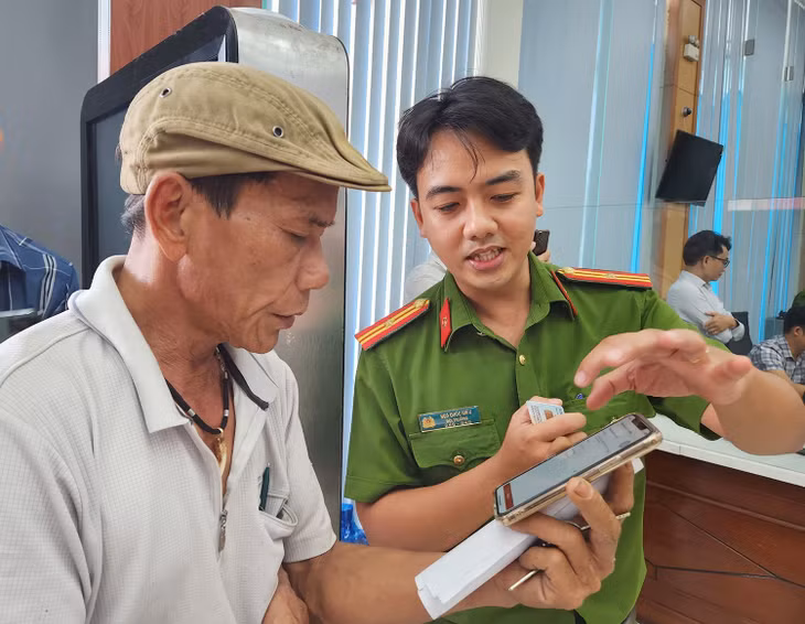 Cán bộ công an hướng dẫn người dân thao tác xin cấp phiếu lý lịch tư pháp trên ứng dụng VNeID tại Trung tâm Phục vụ hành chính công tỉnh Thừa Thiên - Huế_Ảnh: TTXVN