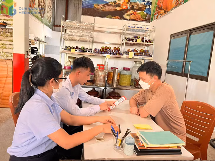 Cán bộ xã Tiền An phối hợp cùng ngân hàng tuyên truyền, hỗ trợ tiểu thương trên địa bàn tạo mã QR thanh toán không dùng tiền mặt.