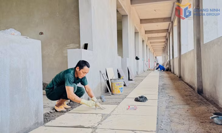 Công nhân đang thực hiện ốp lát nền các khối nhà Trường THCS Hồng Thái Đông.