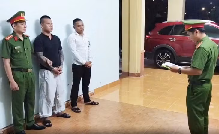 Cơ quan điều tra đọc quyết định tạm giữ hình sự 2 nam thanh niên có hành vi rút súng đe dọa giết người, gây rối trật tự công cộng - Ảnh: TRANG PHƯƠNG