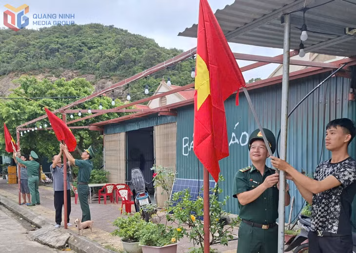CBCS Đồn Biên phòng Đảo Trần trao tặng và giúp người dân trên đảo treo cờ Tổ quốc. 