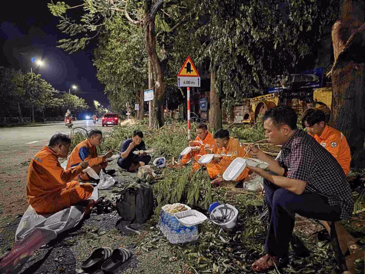 Công nhân điện lực Nghệ An tranh thủ ăn cơm để khắc phục sự số lưới điện sau bão số 5. Ảnh: Ngọc Anh