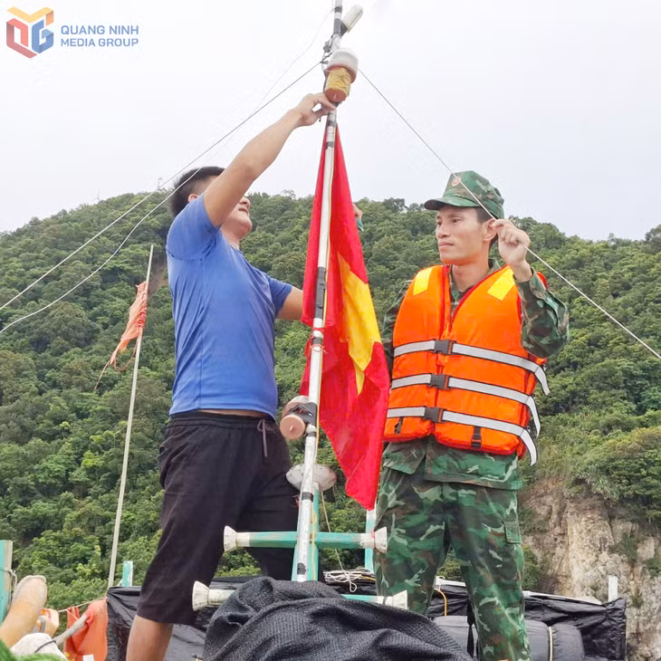 Cán bộ Đồn Biên phòng Đảo Trần giúp ngư dân treo cờ Tổ quốc. (Ảnh: Đồn BP Đảo Trần)