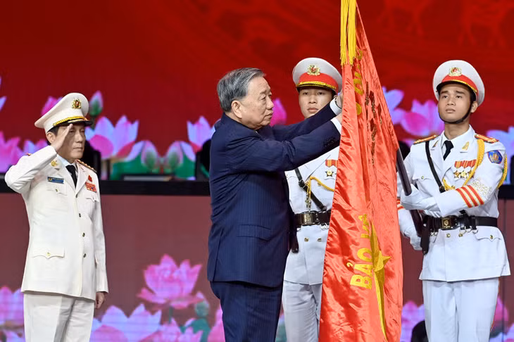 Tổng Bí thư Tô Lâm gắn Huân chương Sao Vàng lên lá cờ truyền thống của Lực lượng Công an nhân dân Việt Nam. (Ảnh ĐĂNG KHOA)