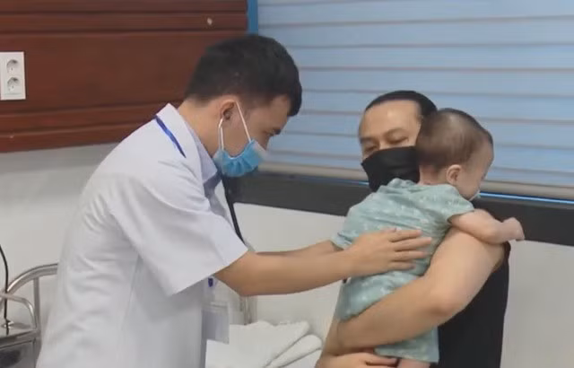 Bác sĩ kiểm tra hô hấp cho trẻ mắc cúm A tại bệnh viện nhi trong mùa dịch.