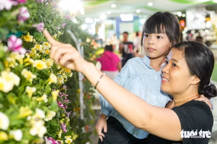 Chị Tuyết Lam cùng con trải nghiệm mô hình trồng hoa thông minh ứng dụng IoT, mô hình ứng dụng cảm biến và tưới tự động, giúp cây phát triển tối ưu mà không cần chăm sóc thủ công - Ảnh: HỮU HẠNH