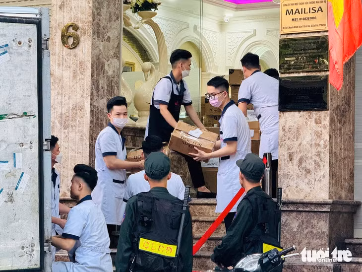 Cảnh sát cùng nhân viên thẩm mỹ viện Mailisa bốc xếp các thùng đồ lên xe tải sau gần một ngày kiểm tra - Ảnh: DANH TRỌNG
