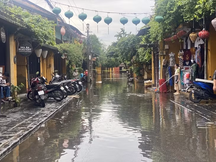 Khúc đường hai đầu Chùa Cầu nước ngập trở lại nhưng cửa hàng vẫn mở cửa - Ảnh: B.D.