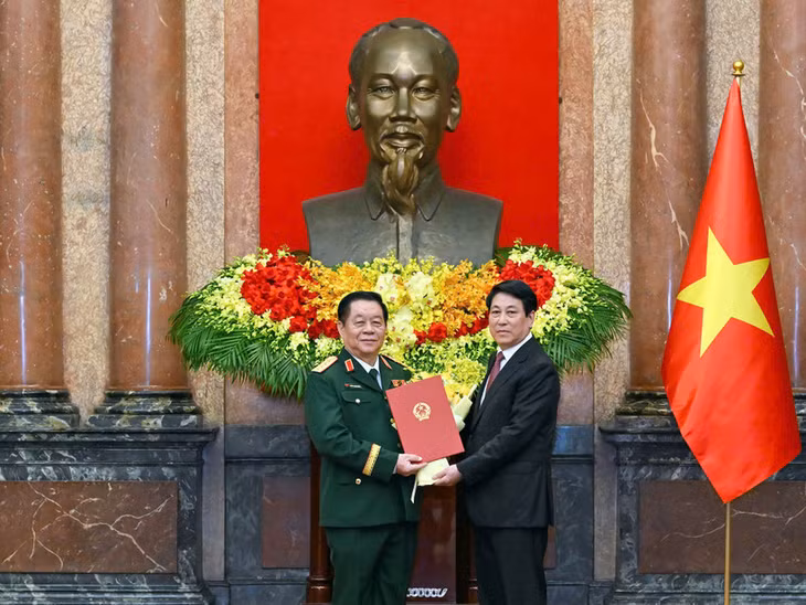 Chủ tịch nước Lương Cường trao quyết định và tặng hoa chúc mừng đồng chí Nguyễn Trọng Nghĩa. (Ảnh: THỦY NGUYÊN)