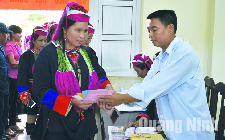 Anh Nịnh Văn Bằng, thành viên tổ bầu cử số 1, thôn Khe Tâm, xã Nam Sơn (Ba Chẽ) hướng dẫn cử tri đồng bào dân tộc Dao Thanh Y làm thủ tục bỏ phiếu. Ảnh: Hồng Nhung