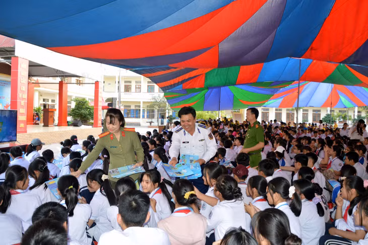 Thiếu tá Bùi Văn Sơn cùng cán bộ công an phát tờ rơi tuyên truyền về tác hại của ma túy cho các em học sinh.