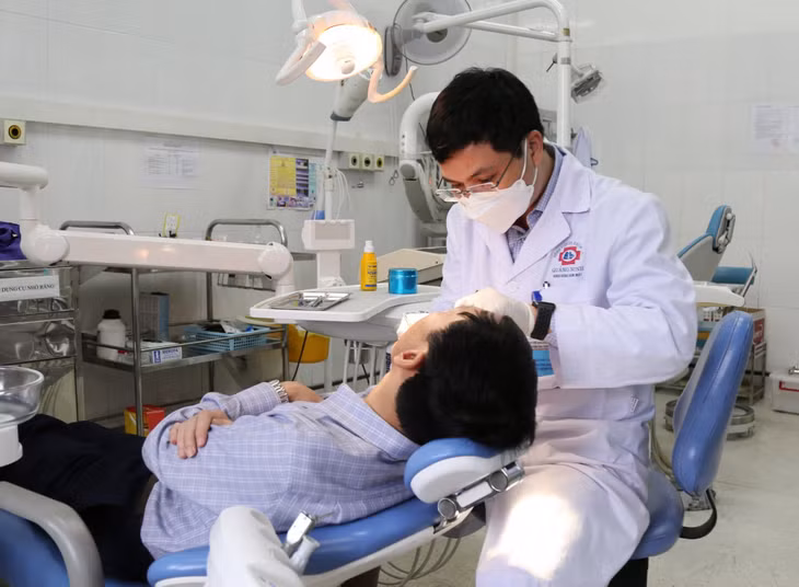 Bác sĩ CKI Nguyễn Văn Tài, Phó Trưởng khoa Khám chữa bệnh theo yêu cầu, Bệnh viện Đa khoa tỉnh, điều trị cho người bệnh tại phòng khám răng.