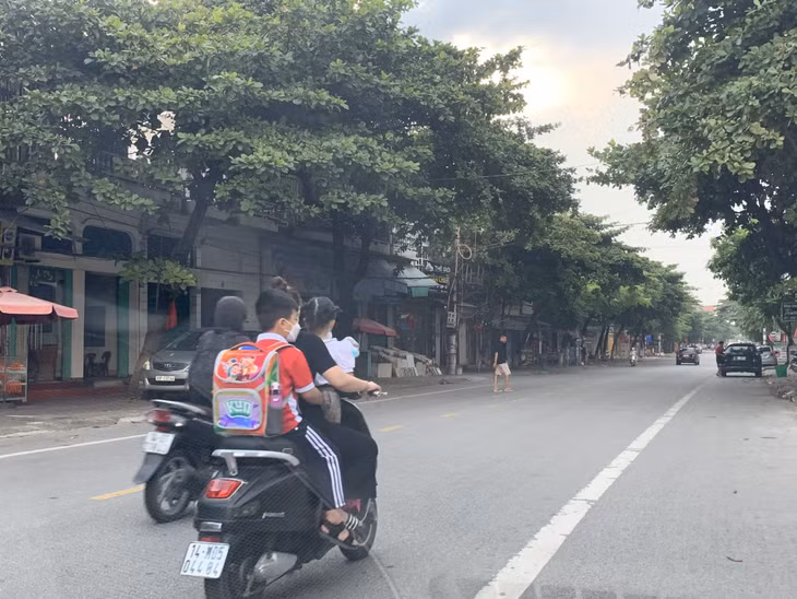 Phụ huynh chở con em mình đến trường không đội mũ bảo hiểm theo quy định. (Ảnh chụp ngày 25/9/2021)