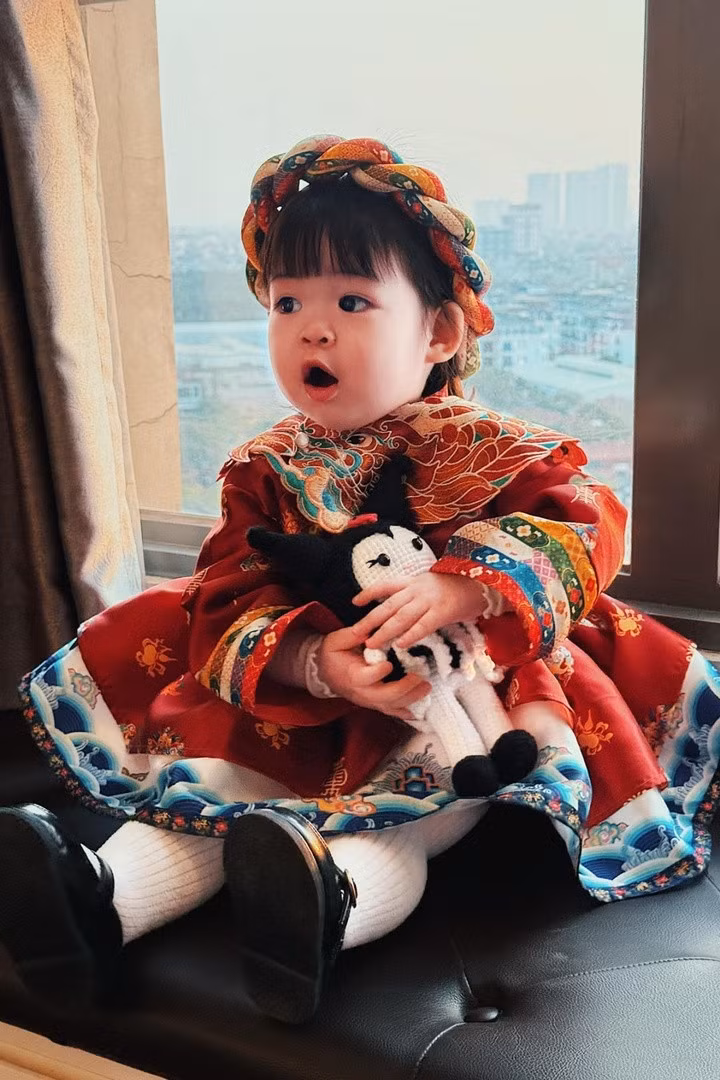 Cô bé diện trang phục sặc sỡ, đầu đội mấn, tạo dáng tinh nghịch.