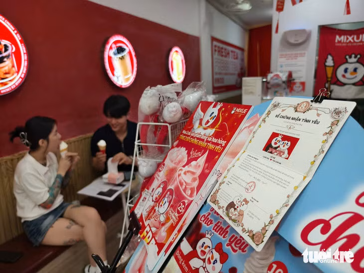 Mua trà sữa được tặng sổ chứng nhận tình yêu viết tên 2 người cùng cơ hội nhận cặp nhẫn vàng 24K - Ảnh: NHẬT XUÂN