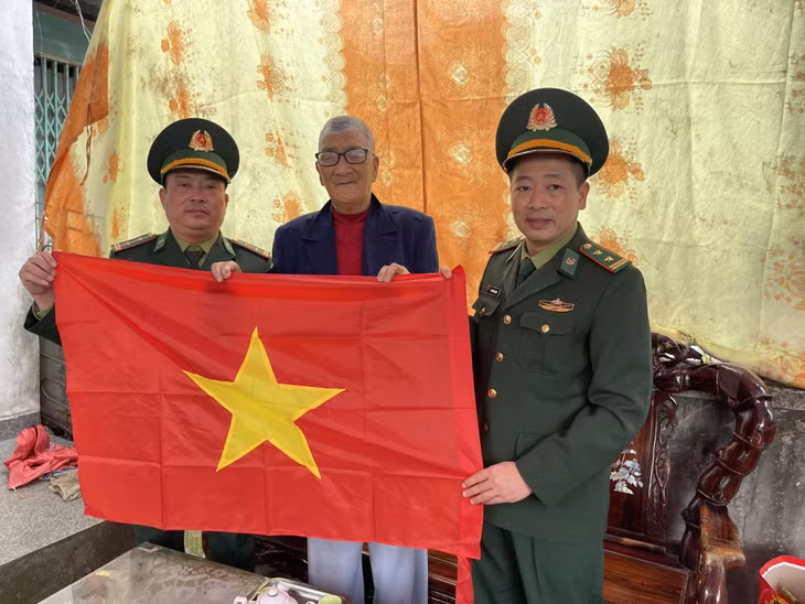 Cán bộ Đồn Biên phòng Trà Cổ tặng cờ Tổ quốc cho ngư dân trên địa bàn phường.
