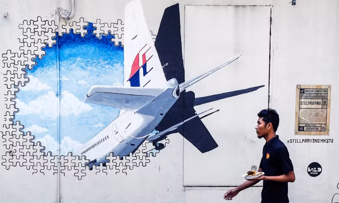 Người Malaysia đi ngang bức tường vẽ tranh tưởng niệm chuyến bay MH370 tại thủ đô Kuala Lumpur tháng 2/2016. Ảnh: AP