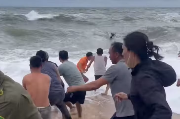 Chính quyền cùng người dân phối hợp dùng dây thừng kéo 3 ngư dân gặp nạn vào bờ. (Ảnh: Văn Nguyễn)