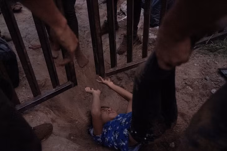 Một đứa một đứa trẻ di cư được kéo qua hàng rào biên giới sau khi vượt sông Rio Grande từ Mexico vào Mỹ ngày 14/7/2022. Ảnh: Reuters