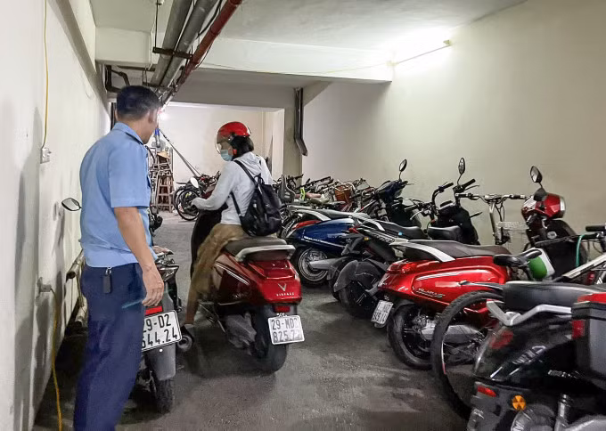 Bảo vệ hướng dẫn người dùng xe điện đỗ ở khu vực riêng. Ảnh: Mạnh Mai