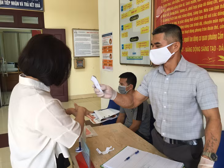 Nhân viên phường Cẩm Thịnh (TP Cẩm Phả) kiểm soát khách ra vào cơ quan nhằm phòng, chống dịch Covid-19. (Ảnh chụp năm 2020, thời điểm dịch Covid-19 đang bùng phát)
