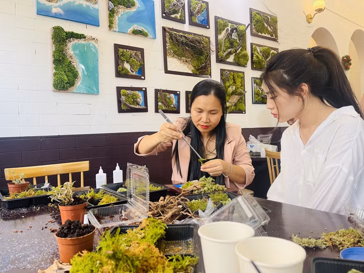 Chị Nguyễn Thanh Hậu (bên trái) hướng dẫn các bạn trẻ làm tranh rêu.