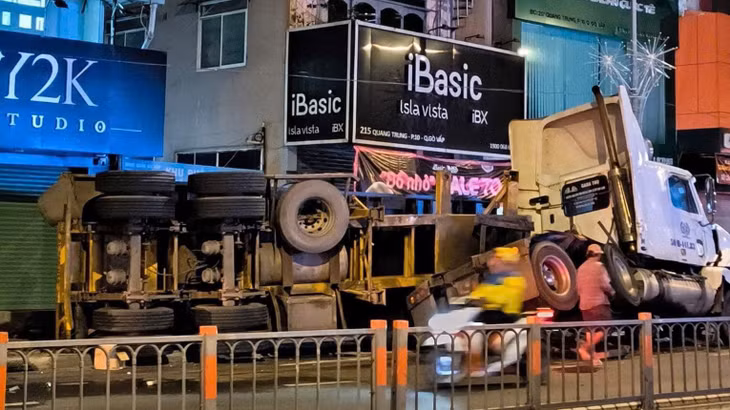 Thùng container lật ngang xuống đường và vỉa hè.