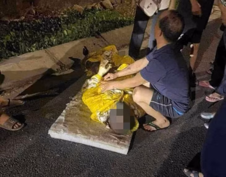 Nạn nhân Đ.V.C được người dân trùm chăn mềm bao phủ vết thương đưa đi cấp cứu.