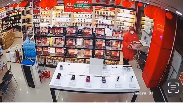 Vàng Ngọc Như mặc áo mưa, đeo khẩu trang vào cửa hàng FPT ở Lào Cai - Ảnh: Cắt từ camera