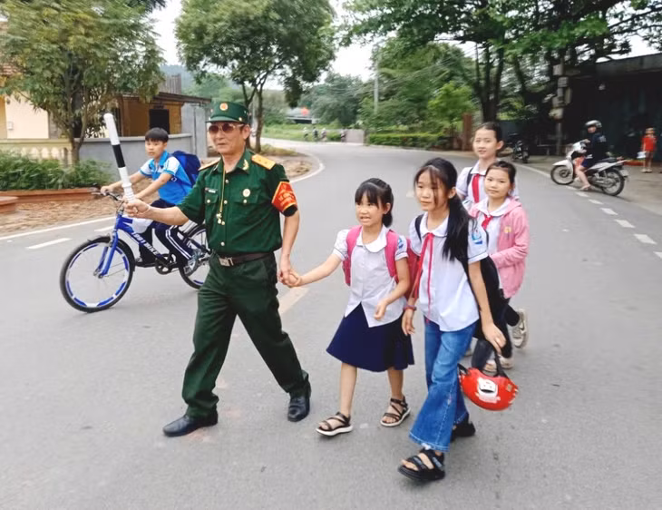 Hội viên CCB xã An Sinh (TP Đông Triều) dẫn học sinh Trường Tiểu học An Sinh qua đường.