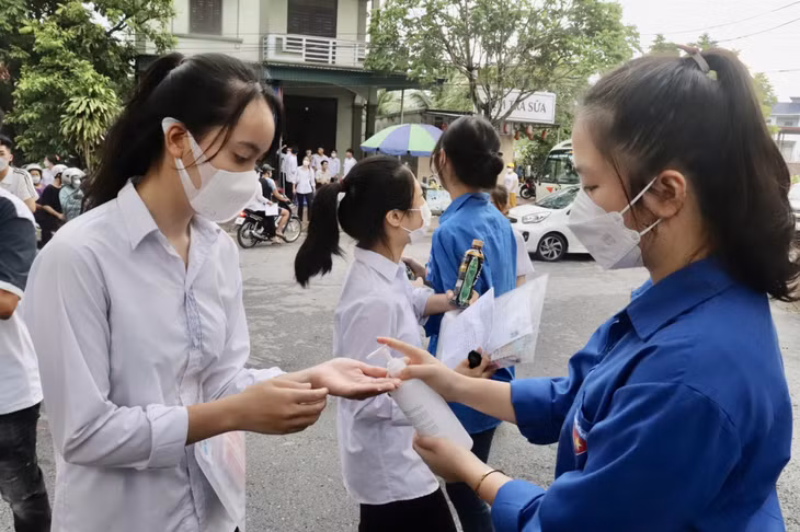 Thanh niên tình nguyện hướng dẫn thí sinh rửa tay sát khuẩn trước khi vào trường thi.