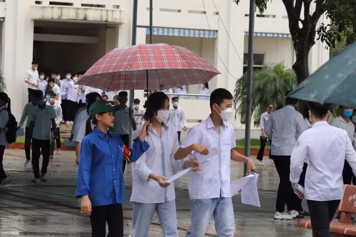 Dưới cơn mưa nặng hạt, các bạn tình nguyện viên trong màu áo xanh vẫn che ô cẩn thận đưa thí sinh từ trường thi ra với người nhà.