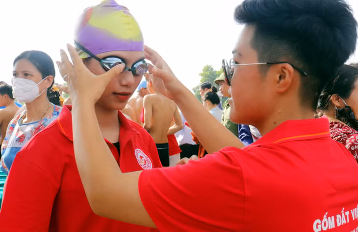 Đồng đội chu đáo sửa kính bơi cho bạn để chuẩn bị bước vào trận đấu.