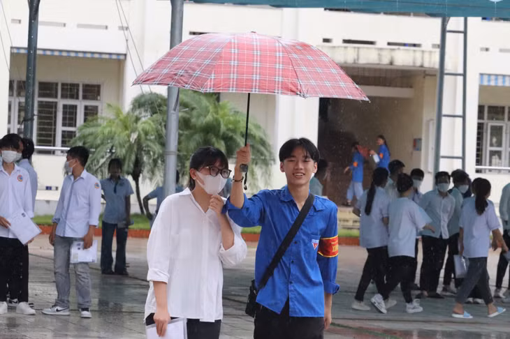 Lực lượng thanh niên tình nguyện tiếp sức mùa thi che ô cho các thí sinh rời điểm thi.