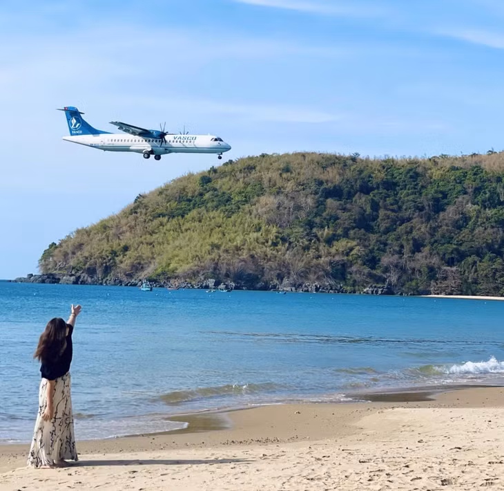 Du khách vừa ngắm biển tại bãi Đầm Trầu, vừa chụp ảnh với máy bay đáp xuống sân bay Côn Đảo - Ảnh: Kim Dung