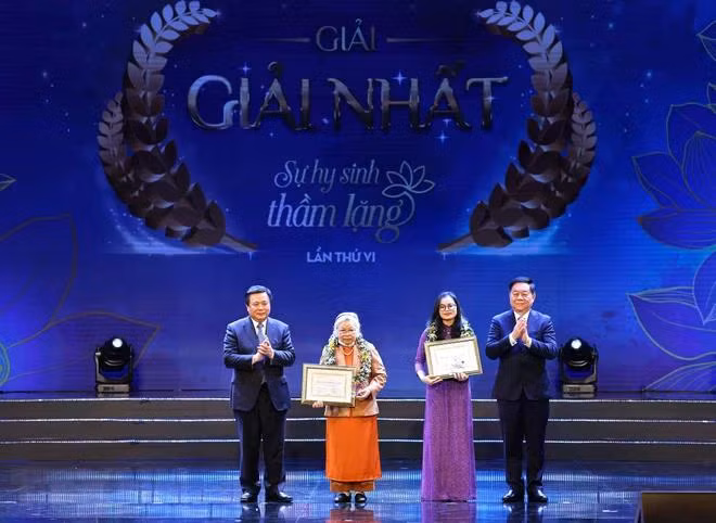 Ông Nguyễn Xuân Thắng, Ủy viên Bộ Chính trị, Giám đốc Học viện Chính trị quốc gia Hồ Chí Minh, Chủ tịch Hội đồng Lý luận Trung ương và ông Nguyễn Trọng Nghĩa, Bí thư Trung ương Đảng, Trưởng ban Tuyên giáo Trung ương trao giải Nhất cho tác giả và chứng nhận cho nhân vật trong tác phẩm đoạt giải. (Ảnh: Thống Nhất/TTXVN)