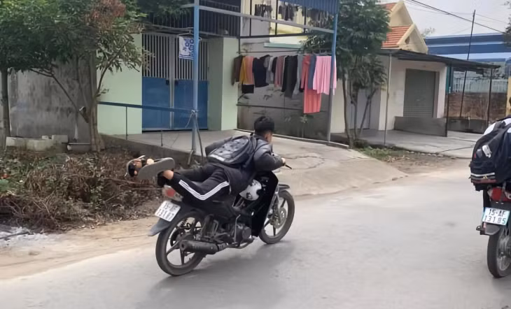 Hình ảnh học sinh Bùi Quốc Th nằm trên yên xe điều khiển phương tiện.
