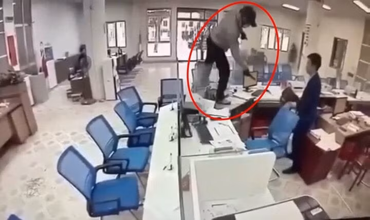 Tên cướp xông vào phía trong quầy giao dịch. (Ảnh cắt từ clip)