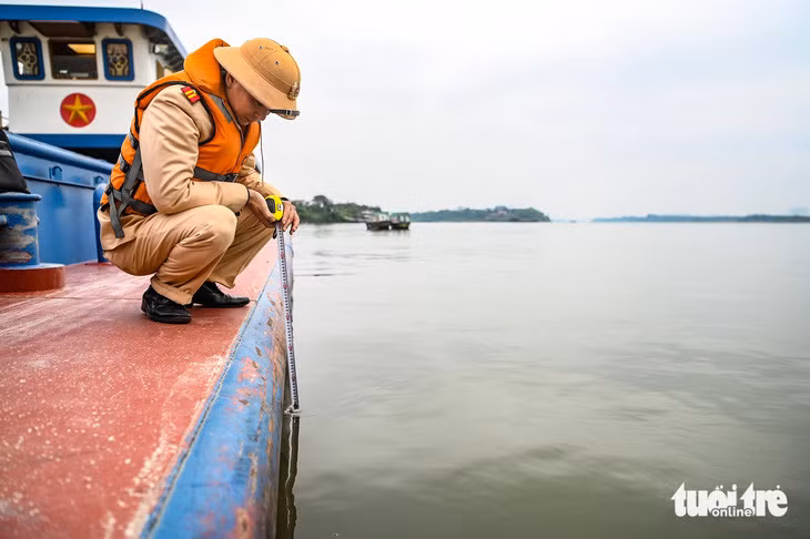 Cảnh sát kiểm tra vạch dấu mớn nước của tàu chở hàng trên sông Hồng - Ảnh: HỒNG QUANG