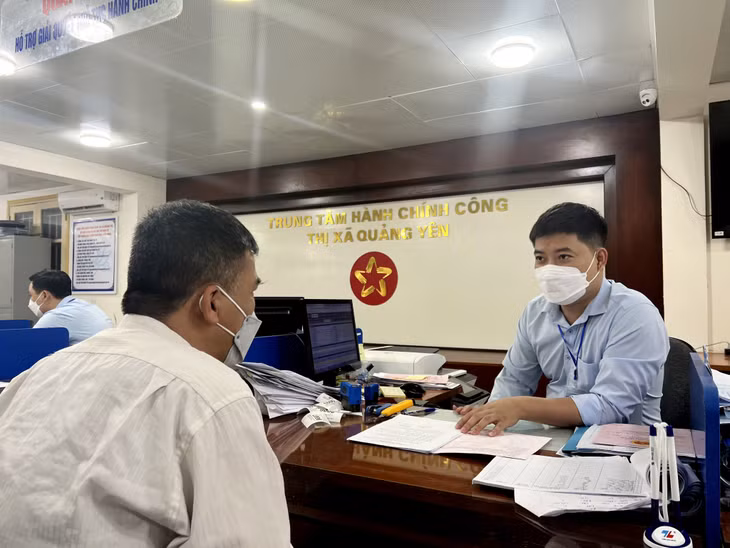 Cán bộ Trung tâm Hành chính công TX Quảng Yên hướng dẫn ông Trần Trí Dũng (phường Quảng Yên) giải quyết TTHC.