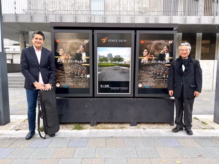 NSƯT Bùi Công Duy và và nhạc trưởng Honna Tetsuji chụp cùng poster chương trình trên đường phố Nhật Bản.